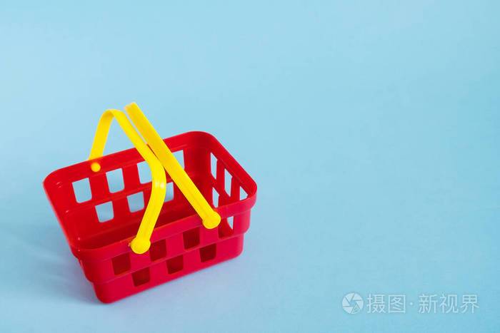 蓝色背景上隔离的红色空玩具塑料购物篮销售和购物概念复制空间